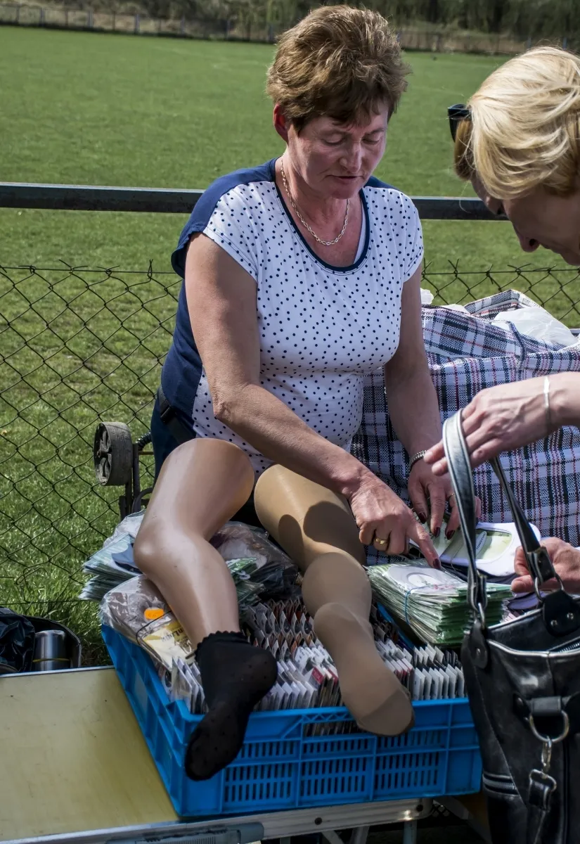 Market vendor sorting goods beside two mannequin legs displayed on her stall